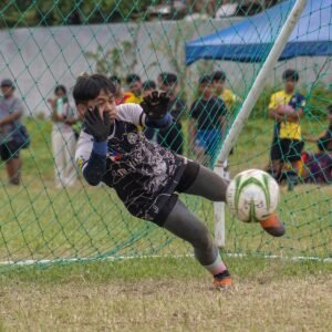 a young boy kicking a soccer ball on top of a field